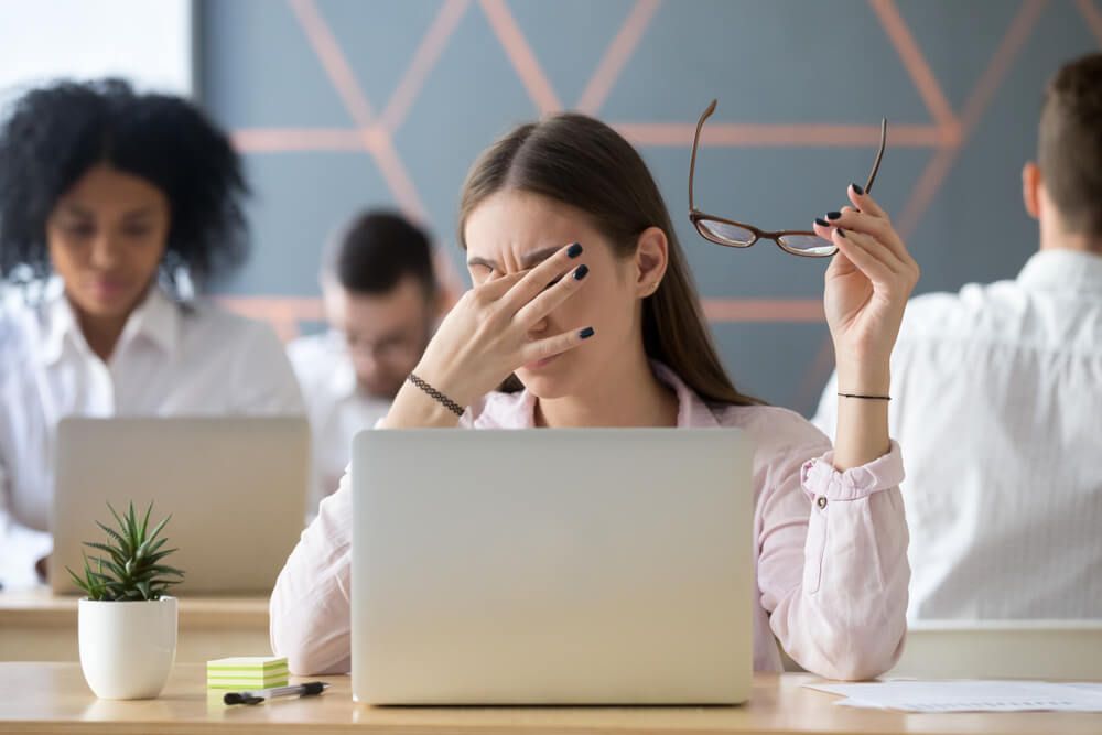 Girls rubbing their eyes while using a laptop.